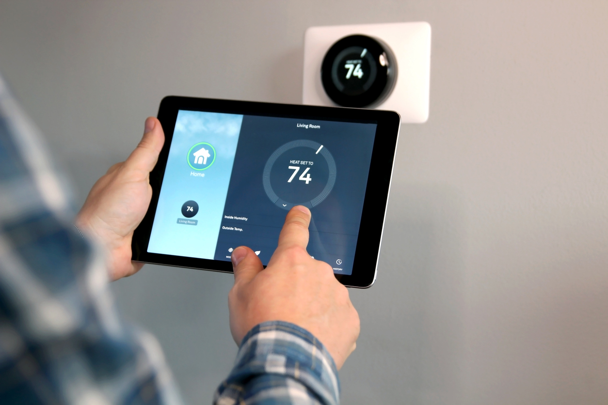 Person using a tablet to control a newly installed smart thermostat in Sacramento, set to 74 degrees.